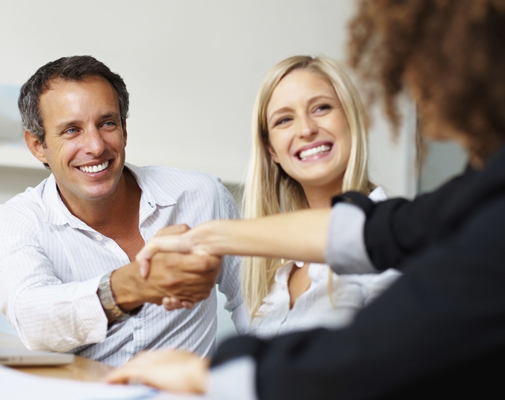Business man shaking hands with female colleague and smiling during meeting